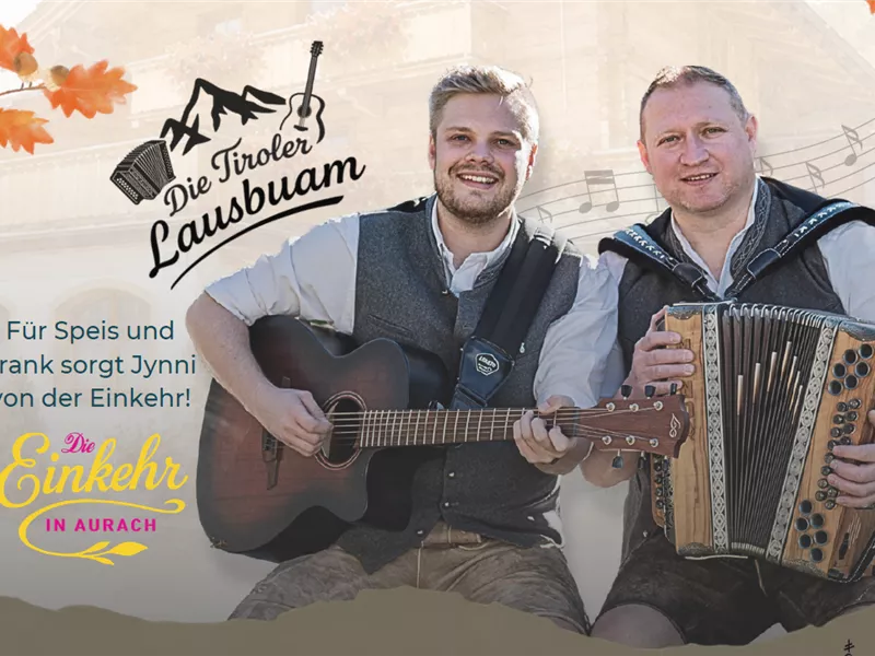 Zwei Musiker in Tracht mit Gitarre und Harmonika vor einem Holzhaus.