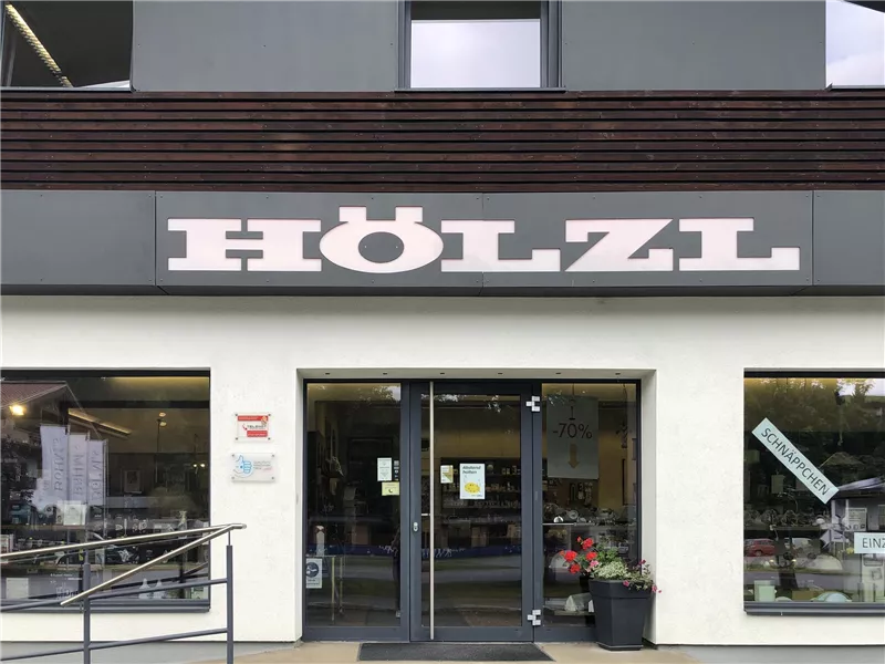 Ein Geschäft mit dem Namen "HÖLZL". Der Eingang ist modern gestaltet und hat große Fenster.