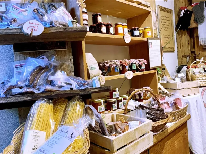 Ein einladender Marktstand mit verschiedenen regionalen Lebensmitteln. Es gibt Nudeln, Marmeladen und handgemachte Produkte in schönen Körben.