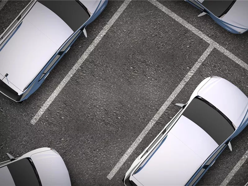 Eine Reihe von Autos auf einem Parkplatz. Die Fahrzeuge sind geordnet in den Parkbuchten angeordnet.
