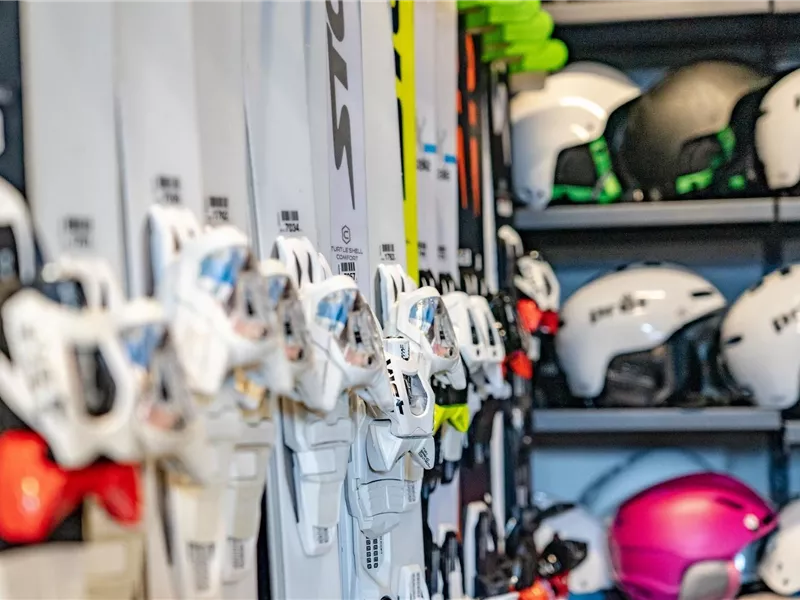 Ski und Helme stehen ordentlich in einem Lagerregal. Die Ausrüstung ist bereit für den nächsten Winterabenteuer.