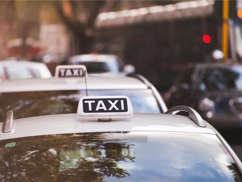 Mehrere Taxis stehen in einer urbanen Umgebung. Die Fahrzeuge haben das typischen Signaltaxi-Schild auf dem Dach.