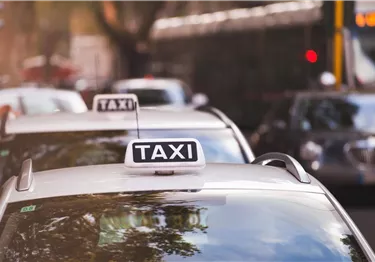 Eine Reihe von Taxis steht in einer Straße. Die Fahrzeuge sind gut sichtbar mit einem Taxi-Schild auf dem Dach.